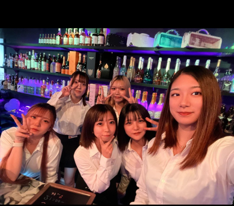 バーカウンターの前で写真を撮る若い女の子6人